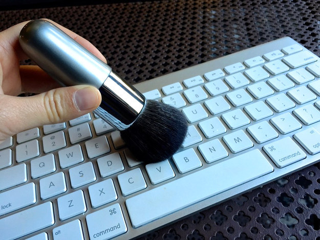 First, run a soft makeup brush in between the keys.